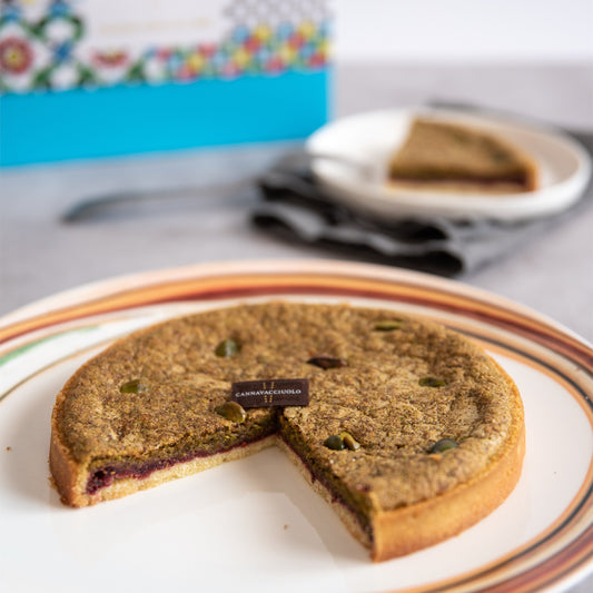 Fetta di crostata pistacchi e ribes servita nel piatto