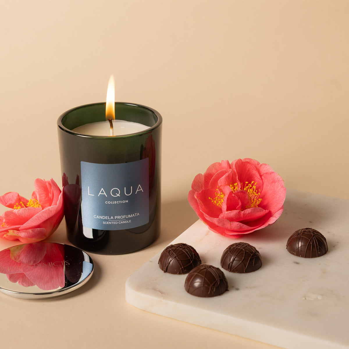 Candela profumata Vanille and Cigar accesa con fiori e cioccolatini su marmo