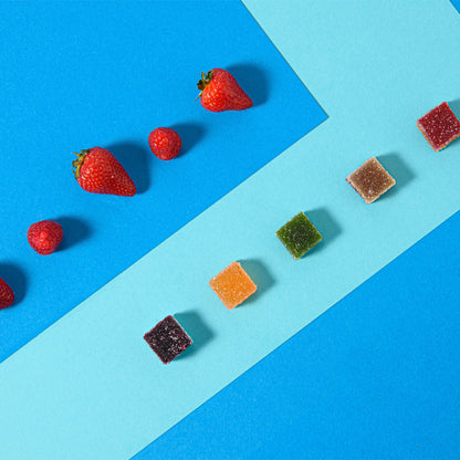 Caramelle gelée alla frutta nei cinque gusti allineate accanto a fragole fresche