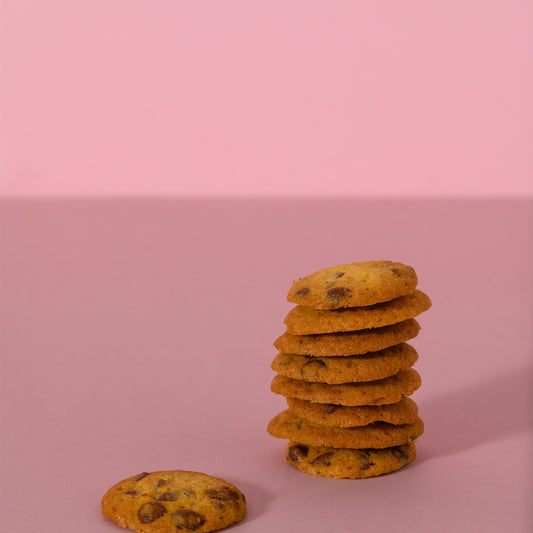 Cookies al cioccolato impilati su sfondo rosa