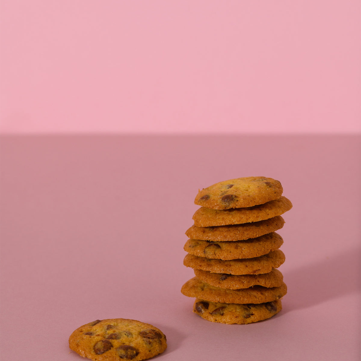 Cookies al cioccolato impilati su sfondo rosa