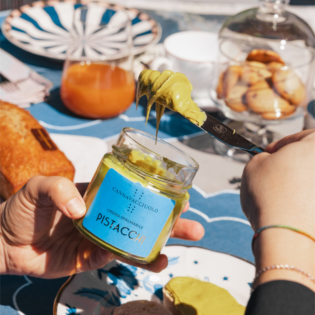 Vasetto di crema spalmabile al pistacchio tenuto in mano a colazione